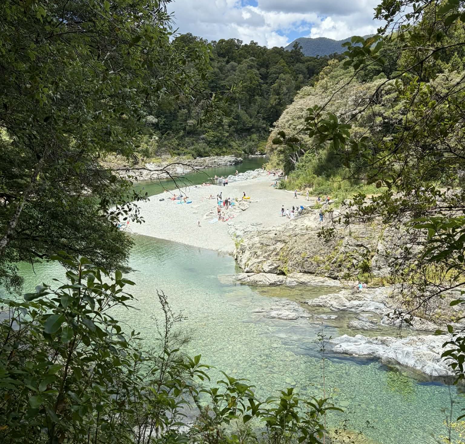 People sunbathing on the rocks next to the crystal clear waters of the Pelorus River